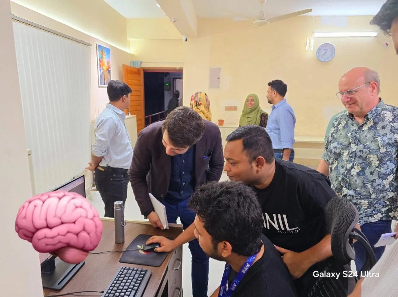 Prinil team members and visiting collaborators reviewing work together at a studio computer.